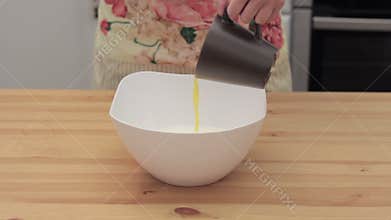 Woman adds ghee in white bowl