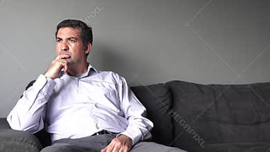 Man in his forties (40s) sitting on a sofa upset.