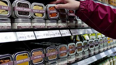 Woman buying cayenne and paprika powders on shelves