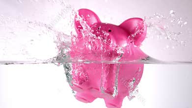 Pink piggy bank falling in water
