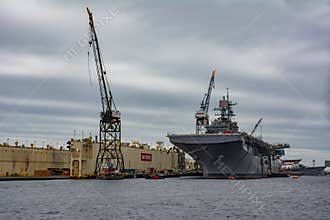 Aircraft carrier Moored dockside by large Crain