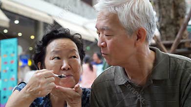 Video Asian senior couple eating an ice cream and feed each other abstract eternal love