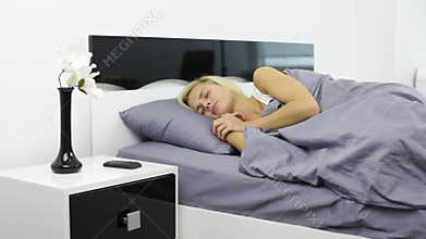 Woman turning off alarm clock phone lying in bed