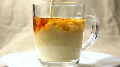 Super slow motion video of adding milk to black tea in a glass mug