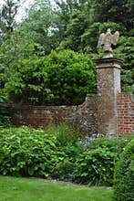 Flower Border and Eagle Sculpture on Old Brick Wall, Tintinhull Garden, Somerset, England, UK