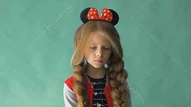 Little girl with braids and a bow in her hair. Posing in the studio