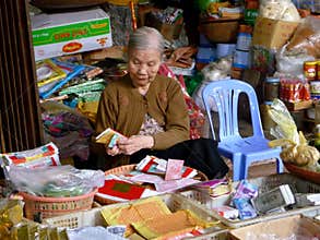 Old woman counting money in her stall on a local market