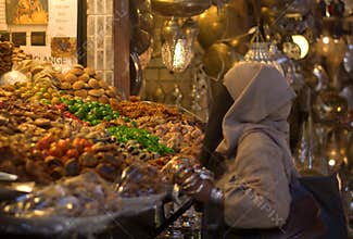 Arabian woman doing the expense of sweets and dried fruits