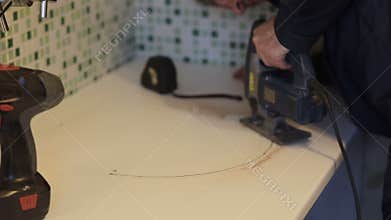 Man worker using a fret saw. kitchen assembly.