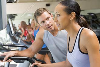 Personal Trainer Encouraging Woman Using Treadmill