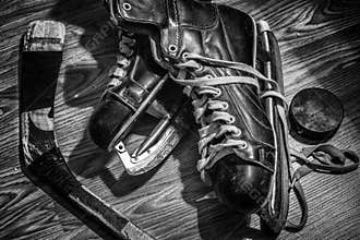 Old pair of mens skates with puck and stick.