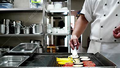 Chief-cooker prepares vegetables on professionally grilled at the restaurant, peppers tomatoes Eggplant fried on a hot