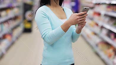Woman with smartphone at supermarket or store