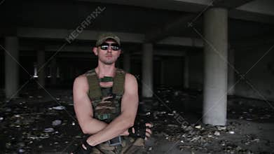 muscular man dancer in military clothes and dark glasses dances. Long shot.