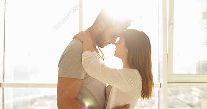 Young Mixed Race Couple Apartment Big Window Morning Sunlight, Cute Happy Hispanic Man And Asian Woman Embracing