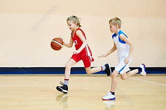 Girl and boy athlete in uniform playing basketball