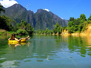 Tourist going down Nam Song River in a tube surrounded by karst