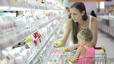 Young woman with cute daughter choosing a yogurt in grocery shopping mall