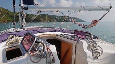 Sail boat in the sea with a man relaxing in the hammock