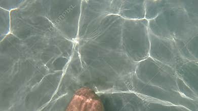 Man's feet walking under sea