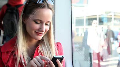 Young blond woman sitting in tram, typing on mobile, phone, cell