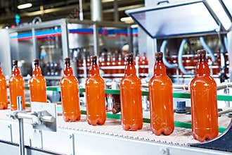 Plastic bottles with beer or carbonated beverage moving on conveyor