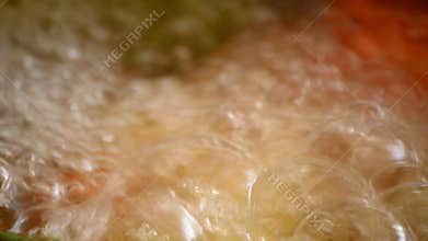 Bubbles of tomato and pepper soup boiling in a pot in a kitchen