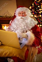 Santa Claus reading email on laptop requesting wish present list